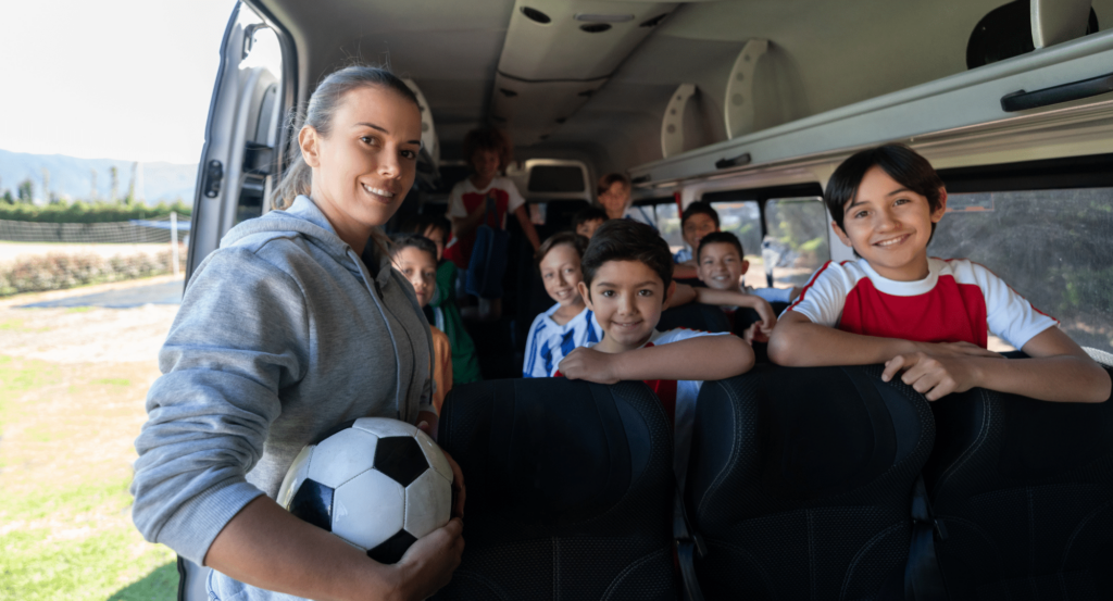 Female adult standing next to kids in a bus